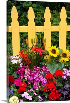 a yellow picket fence surrounded by colorful flowers