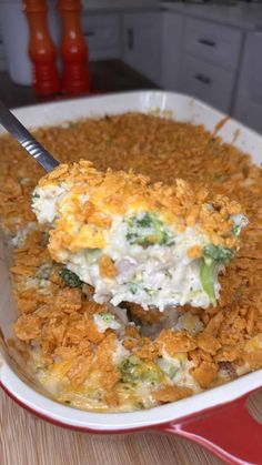 a casserole dish with broccoli and cheese being lifted by a spatula