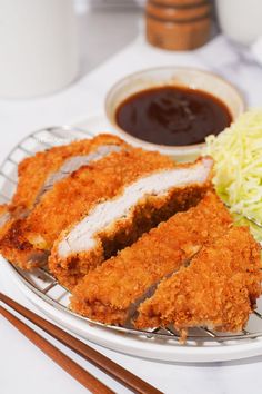 fried chicken with coleslaw and dipping sauce on a plate next to chopsticks