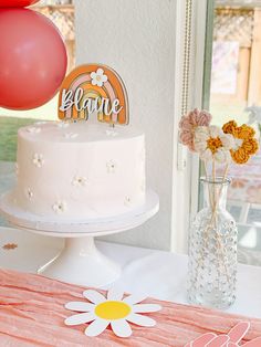 a white cake sitting on top of a table next to a vase filled with flowers