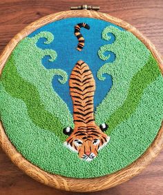 a close up of a embroidery on a wooden surface with a tiger in the grass