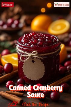 a jar of cranberry sauce next to oranges and cinnamon sticks