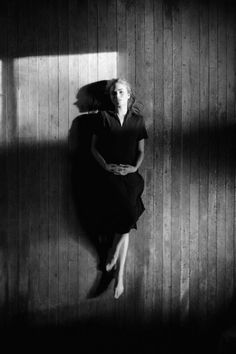 black and white photograph of a woman sitting on a wall with her shadow cast on the wall