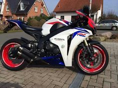 a white and red motorcycle parked on the side of a road next to a house