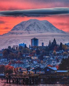 a view of a city with a mountain in the background and clouds above it at sunset