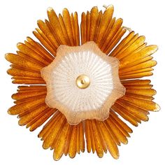 an orange and white flower shaped brooch with gold accents on it's center