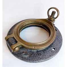 an old brass plated metal clamp on a white table top with a hole in the middle