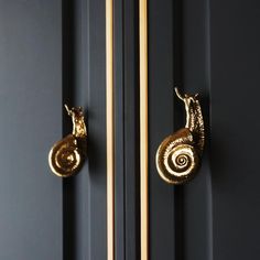 the door handle is gold and has two snails on it