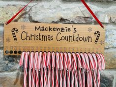 a wooden sign hanging from the side of a brick wall next to candy canes