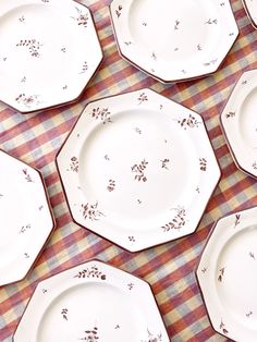 many plates are lined up on a table with red and white checkered cloths