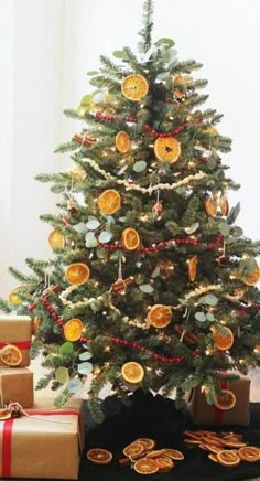 a small christmas tree with orange slices on it and presents under the tree in front of it