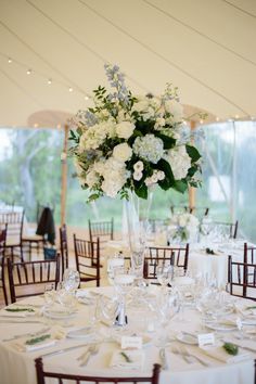 a table set up with white flowers and place settings