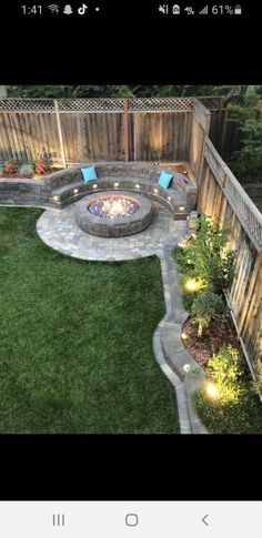 an outdoor fire pit in the middle of a yard with grass and lights around it