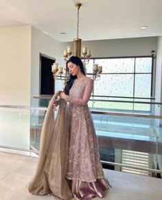 a woman standing in front of a chandelier wearing a pink and gold gown