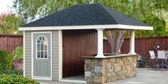 a small backyard shed with a stone wall and roof