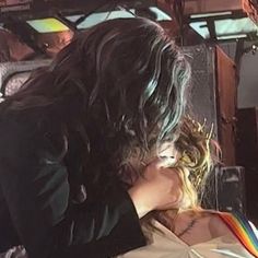 a woman with long hair sitting on top of a bed next to a man in a suit