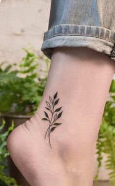 a woman's foot with a small black plant tattoo on the left side of her ankle