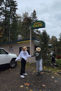 two people holding hands in front of a car dealership with a sign that says the coffee cafe