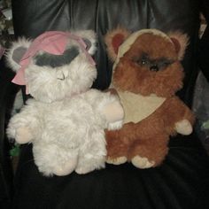 two stuffed animals sitting next to each other on a black leather chair in a room