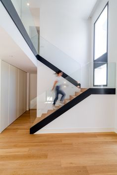 a person walking up the stairs in a house with wood floors and white walls,