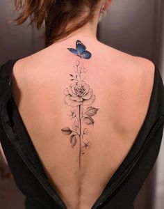 the back of a woman's neck with a flower and butterfly tattoo on it