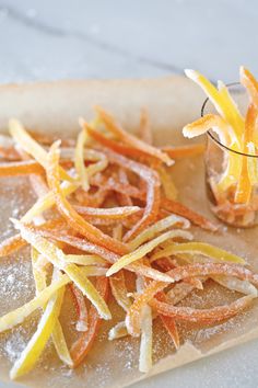 sliced orange peels on a cutting board next to a small glass with something in it