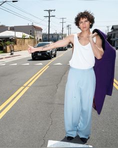 a man standing on top of a skateboard in the middle of the road with his arms outstretched