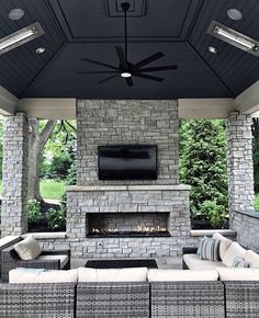 an outdoor living area with couches, fireplace and flat screen tv on the wall