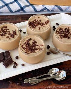 three desserts on a white plate with spoons and chocolate chips next to them