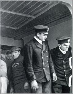 black and white photograph of men in uniforms on a ship, looking out the window