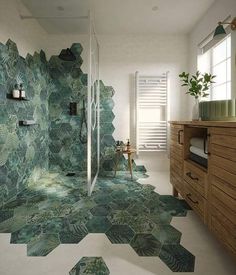 a bathroom with green tiles on the floor and walls, along with a wooden cabinet