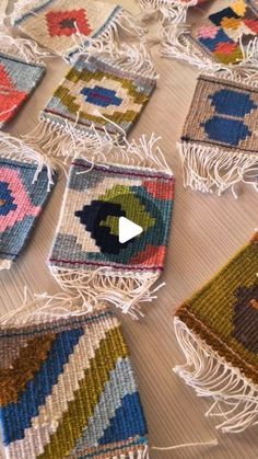 a table topped with lots of colorful rugs on top of a wooden floor covered in tassels