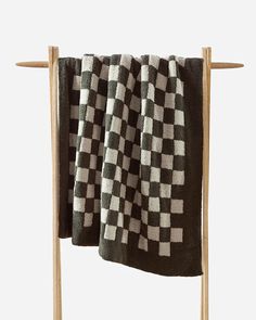 a black and white checkered towel hanging on a clothes rack with two wooden pegs