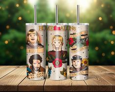 three travel mugs with the faces of people on them sitting on a wooden table