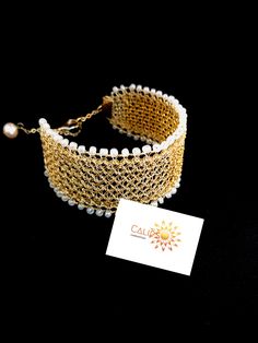 a gold bracelet with pearls and a card on the side that says call me now