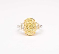 an oval yellow diamond ring with three baguets