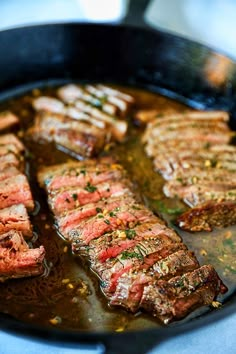 some steaks are cooking in a skillet on the stove top with sauce and seasoning