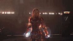 iron man standing in the dark with his hands on his hips and glowing lights behind him