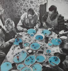 a group of people sitting around a table with blue dishes on it