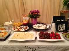 a table topped with plates of food next to a vase filled with flowers and fruit