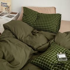 an unmade bed with green sheets and pillows