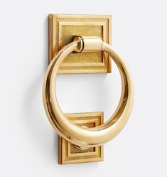 an image of a gold door handle on a white wall with the letter o in it