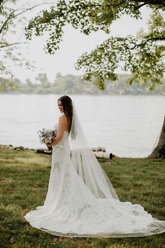 a woman in a wedding dress standing by the water