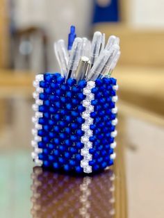 a blue and white beaded pen holder sitting on top of a table