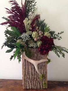 a vase filled with flowers and greenery on top of a wooden table