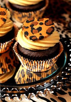 chocolate cupcakes with yellow frosting and leopard print icing on a glass plate