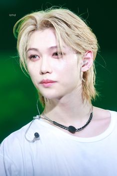 a woman with blonde hair wearing a white shirt and black beaded necklace on her neck