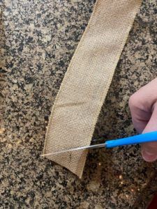 a person is holding a pair of scissors in front of a piece of burlock