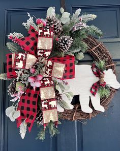 a christmas wreath hanging on the front door with moose decorations and pine cones around it