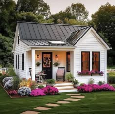 a small white house with flowers in the front yard